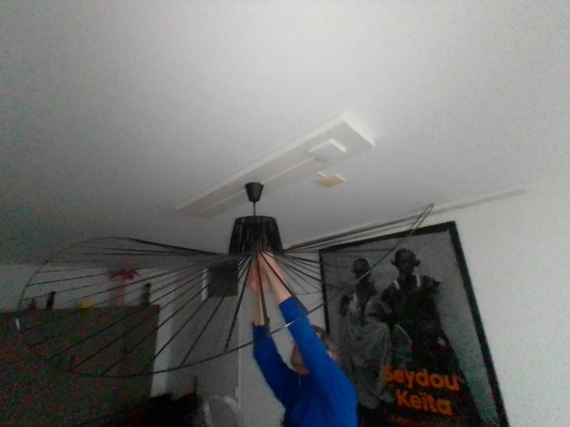 Ophangen van een grote design hanglamp aan het plafond van een woonkamer