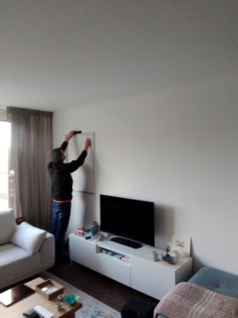 Whiteboard waterpas ophangen aan de wand van een woonkamer